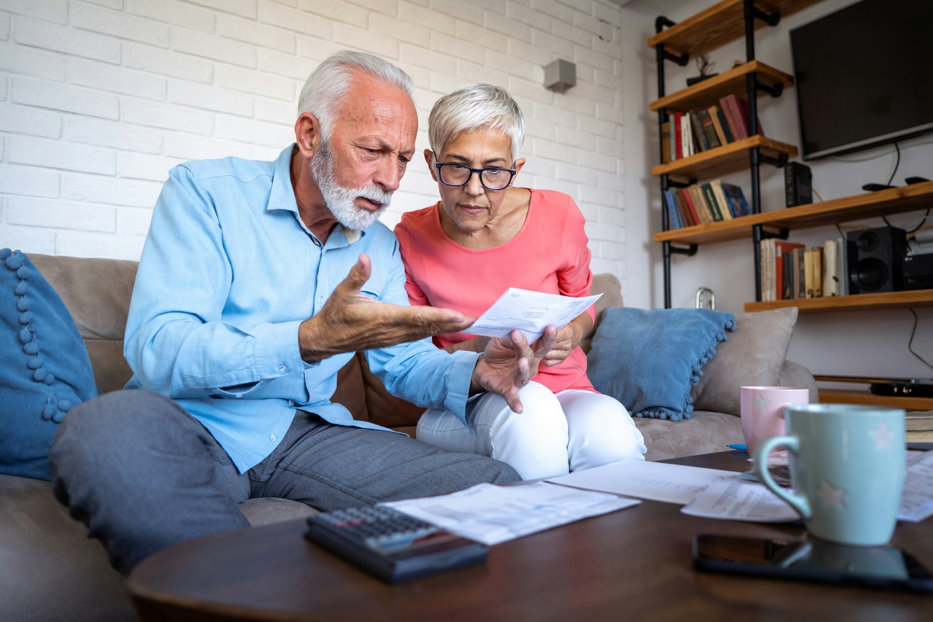 Image of worried senior couple counting bills at home