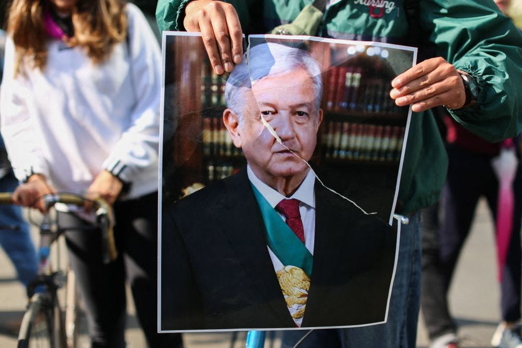 Image of a poster of Mexican President Andrés Manuel López Obrador carried by a demonstrator protesting against the leader.
