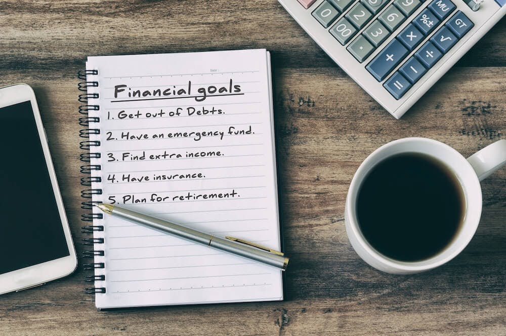 Graphic featuring a notebook with a list of financial goals