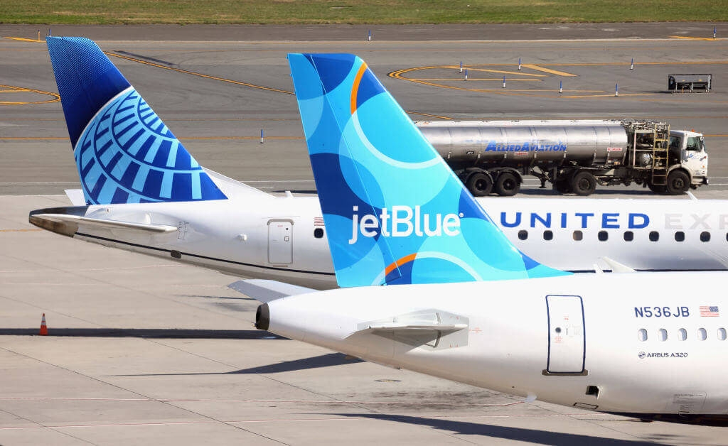 Photograph of airplanes from United Airlines and JetBlue Airways on the taxiway at an airport