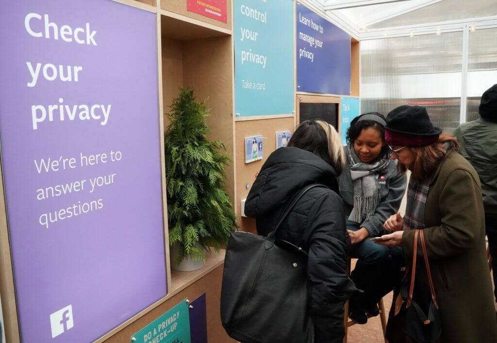 Image of Facebook employees talking to customers in front of a sign referencing data privacy.